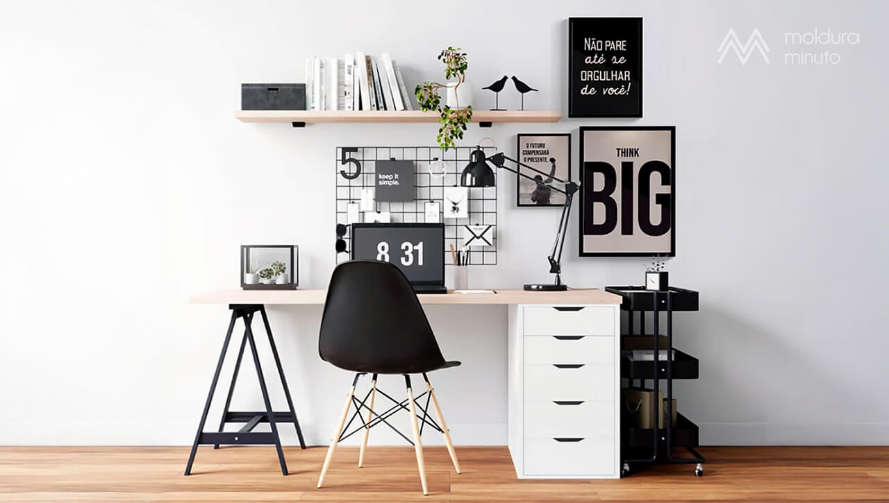 Parede de home office decorada com quadros de frases inspiradoras em tipografia moderna. A mesa tem laptop, luminária e acessórios de papelaria, transmitindo organização e motivação.
